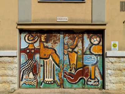 Di Porta Grecia � semplice risalire all�autore, di cui � ben riconoscibile la firma in basso a destra: Yulianos Kattinis. Servendosi di colori accesi, rappresent� simboli classici legati ai valori dello sport intersecati tra loro su un piano bidimensionale